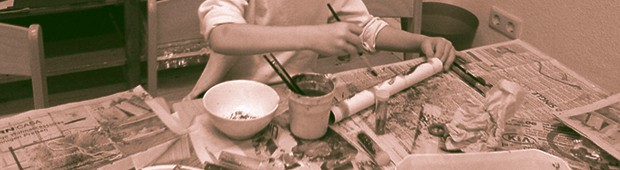 Die Arme eines Kindes das mit Pappmache spielt