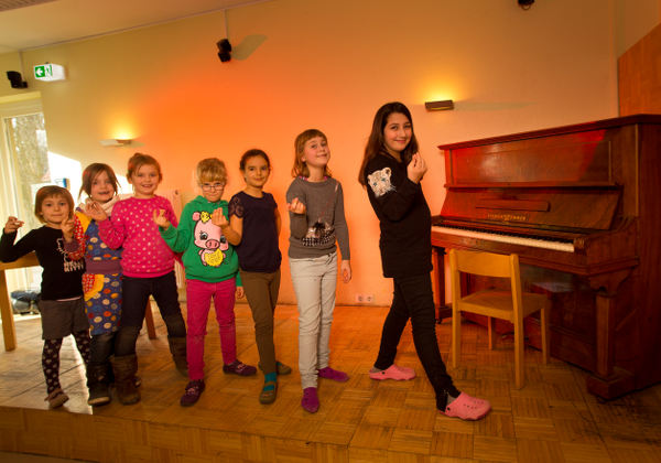 Kinder in einer Reihe vor einem Klavier