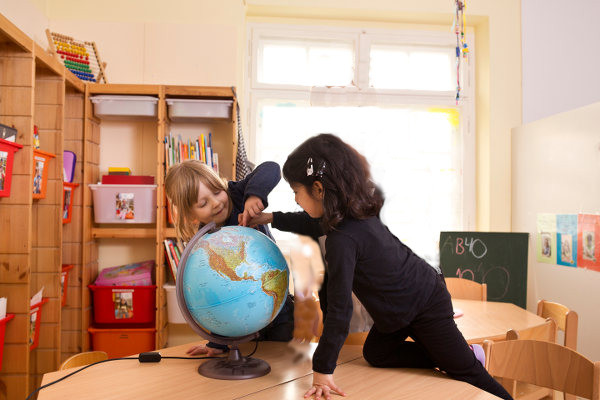 Zwei Kinder spielen mit dem Globus